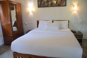 1 dormitorio con 1 cama grande con sábanas y almohadas blancas en Laliguras Villa 200 Mts from candolim beach, en Candolim