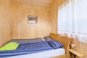 Cama en habitación de madera con ventana en Tiny-Ferienhäusle Casa Wendy en Loßburg