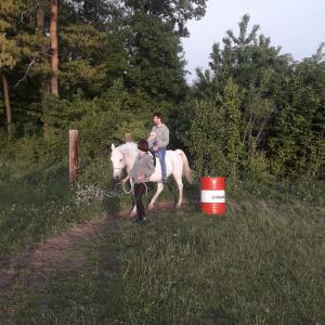 a man riding a white horse with a child on it at Ranč pod Žobrákom in Čekovce