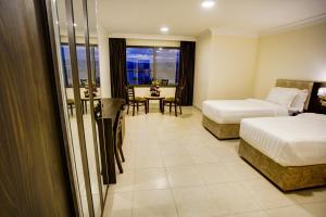 Habitación de hotel con 2 camas y mesa en AQABA COAST HOTEL en Áqaba