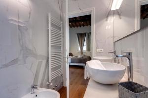 La salle de bains blanche est pourvue d'une baignoire, d'un lavabo et d'une baignoire. dans l'établissement Mamo Florence - Bonnie - Clyde - Marvin Apartments, à Florence