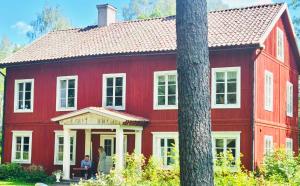 una casa roja con dos personas de pie delante de ella en 5 bed country home only 2 hrs north of Stockholm, en Garpenberg