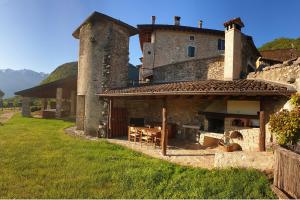 a stone house with an outdoor kitchen in a yard at Agriturismo Al Lambic in Tignale