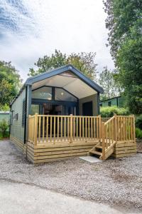 a tiny house with a porch and a deck at Waterfoot Park in Pooley Bridge