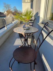 stół i krzesło na balkonie z wazą i rośliną w obiekcie Wohnen beim Brotsommelier - Holzmichel w mieście Darmstadt