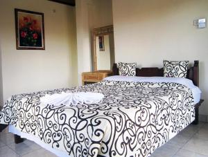 een slaapkamer met een bed met een zwart-witte deken bij Tunjung Guest House in Ubud