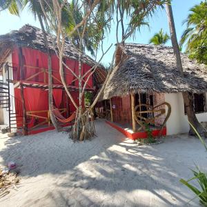 un bâtiment rouge et blanc avec un toit en paille dans l'établissement Karibu Paradaizi, à Michamvi