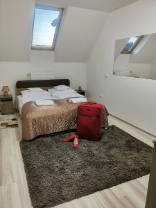 - une chambre avec un lit et une valise rouge sur un tapis dans l'établissement Ferzs Apartman Egerszalók, à Egerszalók