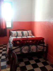 a bedroom with a bed with red walls and a checkered floor at Hôtel Glacier in Fez