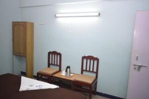 a room with two chairs and a table with a tea kettle on it at Sri Krishna Vilas in Coimbatore