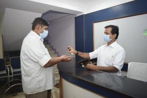 two men standing at a counter in a room wearing masks at Sri Krishna Vilas in Coimbatore