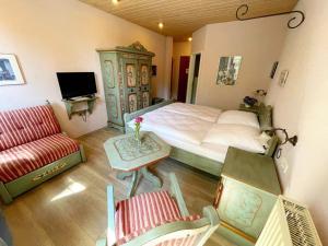 ein Schlafzimmer mit einem Bett, einem TV und einem Sofa in der Unterkunft Bayerischer Hof in Rothenburg ob der Tauber