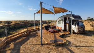 an rv with a deck and awning in a field at Sherman's place - שרמנ'ס פלייס in Melilot