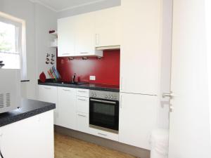 een keuken met witte kasten en een rode muur bij Piratenlodge in Ringsheim