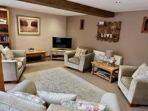 sala de estar con sofás y TV en Waterside Cottages, en Waterhouses
