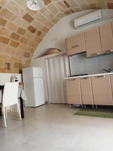 a kitchen with a white refrigerator and a table at GRAZIOSO MONOLOCALE NEL CUORE DEL CENTRO STORICO in Francavilla Fontana