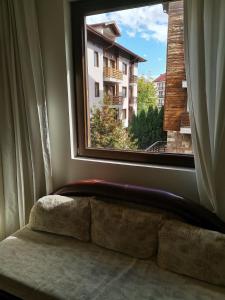 a window with a couch looking out at a building at Fortuna Apartments in Bansko