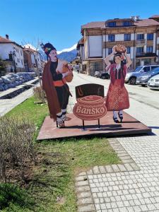 a statue of a man and a girl standing next to a sign at Fortuna Apartments in Bansko