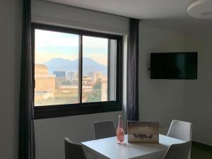 ナポリにあるMondo Suites Apartmentsのテーブルと窓(ボトル付)が備わる客室です。
