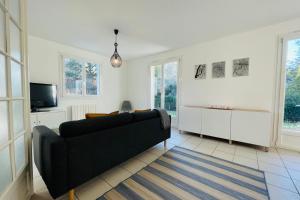 a living room with a black couch and a tv at The House of the Green Way a charming pied-à-terre for your walks in Toura in Joue-les-Tours