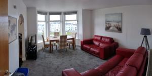 a living room with a red couch and a table at The Gateway Guest Apartment in Portstewart