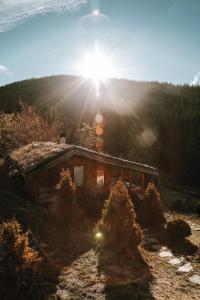a log cabin with the sun shining behind it at Панорама хаус Лещен и еко къщи Дървена и Землянка in Leshten