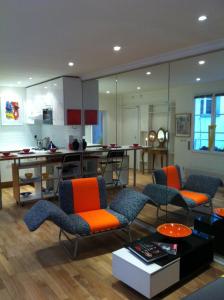 sala de estar con sillas de color naranja y cocina en Into Paris - Louvre Apartment, en París