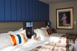 a hotel room with two beds and a blue wall at Pendley Manor in Tring