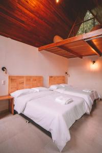 um quarto com uma grande cama branca e um tecto de madeira em KANTU GARDEN LODGE em Moyobamba