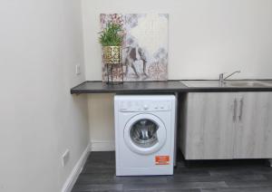 een keuken met een wasmachine onder een aanrecht bij Charming Studio 2 mins Walk To Belgrade Theatre in Coventry