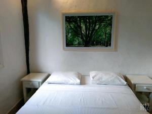 1 dormitorio con 1 cama con 2 mesas y una foto en la pared en Pousada Baobá, en Juquei