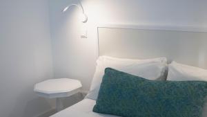 ein Bett mit einem grünen Kissen und einem Nachttisch in der Unterkunft City Balcony in Ponta Delgada + 46 Fotos