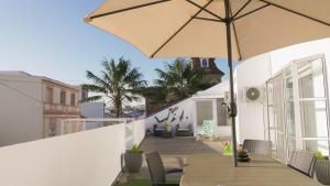 eine Terrasse mit Sonnenschirm auf dem Balkon in der Unterkunft City Balcony in Ponta Delgada