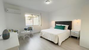 ein weißes Schlafzimmer mit einem Bett und einem Tisch in der Unterkunft City Balcony in Ponta Delgada