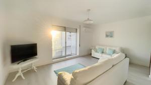 ein Wohnzimmer mit einem weißen Sofa und einem Fernseher in der Unterkunft City Balcony in Ponta Delgada