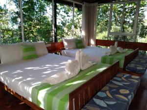 Duas camas num quarto com janelas em Sinharaja Kurulu Ella Eco Resort em Deniyaya