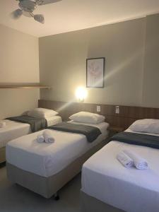 a hotel room with three beds with white sheets at Pousada Bella Nina in Balneário Camboriú
