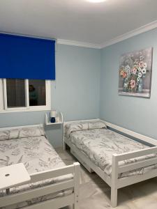 Apartamento céntrico “Los Pajaritos” con garaje. في خيريز دي لا فرونتيرا: سريرين في غرفة بجدران زرقاء