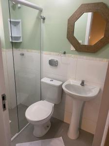 a bathroom with a toilet and a sink and a mirror at Pousada Bella Nina in Balneário Camboriú