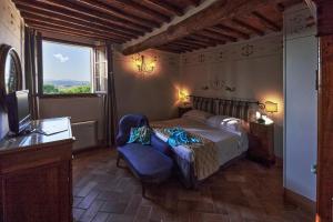 a bedroom with a bed and a chair and a television at Villa Curina Resort in Castelnuovo Berardenga