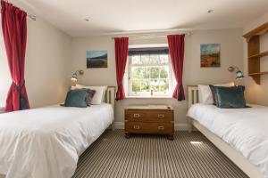 two beds in a room with red curtains at The Dog & Gun Inn in Netheravon