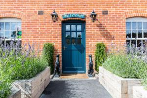 een blauwe deur op een bakstenen gebouw met een welkomstbord bij The Dog & Gun Inn in Netheravon