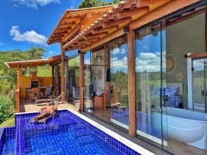 a woman is sitting on a pool next to a house at Chalé Tucano super Luxo in Cunha