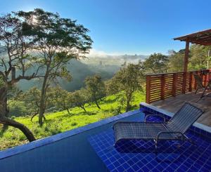 a deck with two chairs and a view of the mountains at Chalé Tucano super Luxo in Cunha