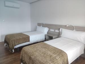 une chambre d'hôtel avec deux lits et une lampe dans l'établissement Alojamientos Central, à O Porriño