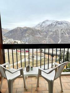 two chairs and a table on a balcony with mountains at Studio au pied des pistes avec vue imprenable sur la station in Orcières
