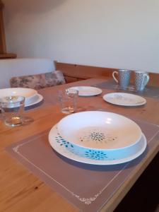 une table avec des assiettes et des verres sur une table en bois dans l'établissement Casa Neve e Sole - presso Sussy Residence, à Falcade