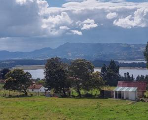 un campo con árboles y vistas al lago en Camping Las Acacias, en Guatavita