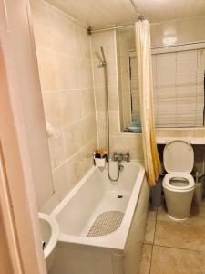 a bathroom with a white tub and a toilet at CROYDON Spacious 3 Bedroom Family House in Addington