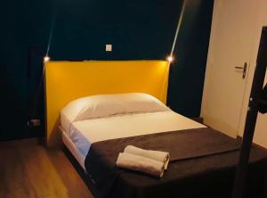 a small bedroom with a bed with a yellow headboard at H&ocirc;tel R&eacute;sidence De Bruxelles in Paris
